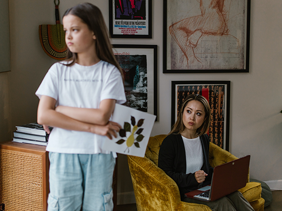A middle school girl with her back to an older woman, who is sitting in a chair behind her