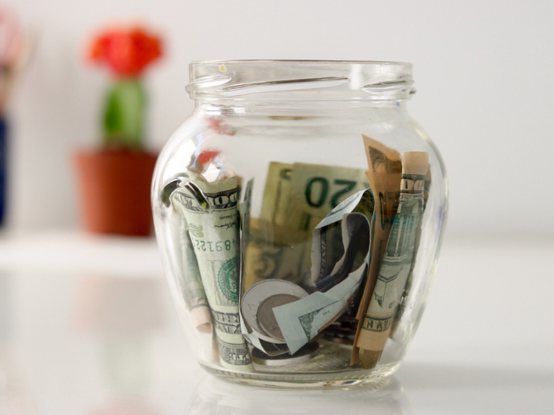 Money tucked into a clear jar