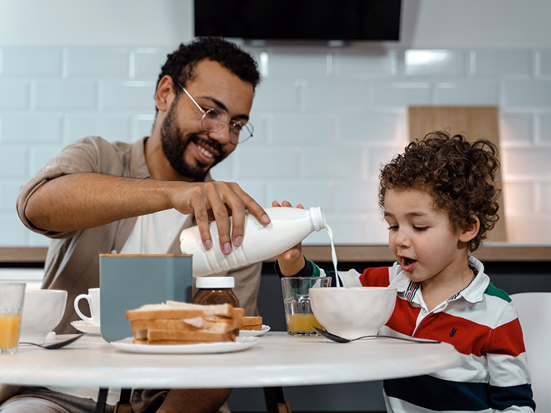 A man and his son eat breakfast at a kitchen table