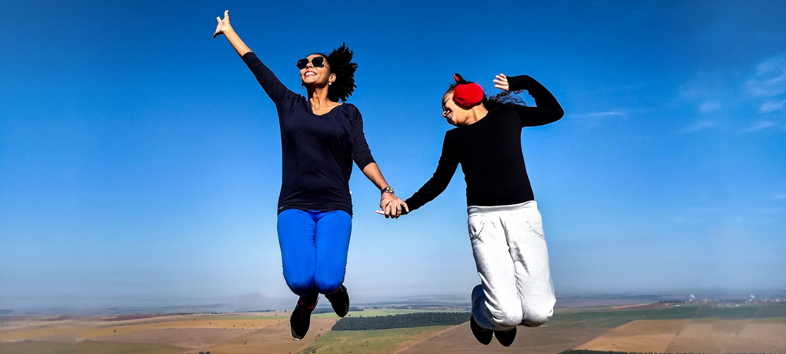 Two women jumping in the air with a blue sky behind them
