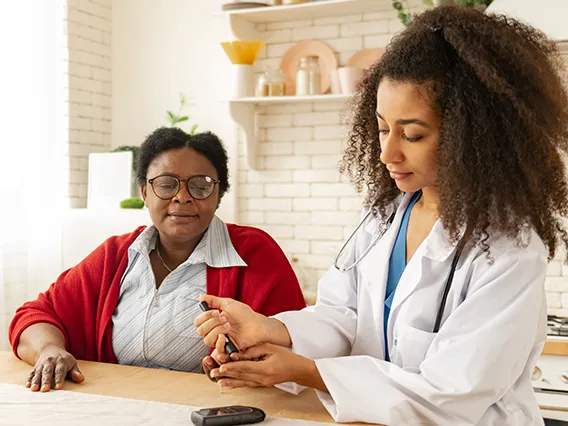 a young female doctor taking a finger stick from an older female patient