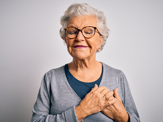 an older woman with her hands on her heart