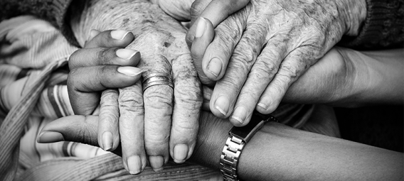 black and white photo of older hands clasped with a younger set of hands.