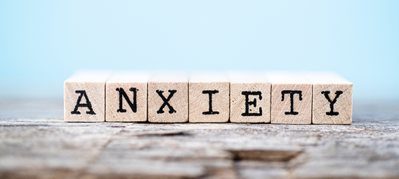 The word anxiety on blocks with a wood and light blue background