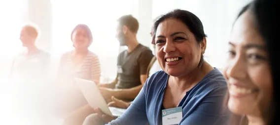 Support group meeting with two women in the foreground smiling