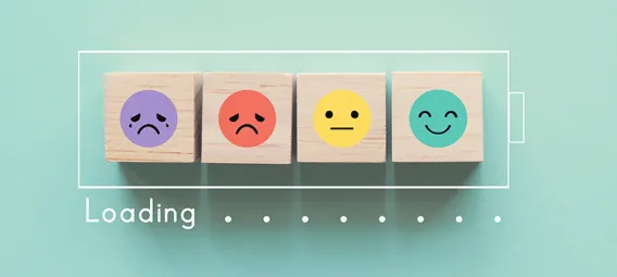 Wooden blocks with faces moving from sad to happy inside a battery outline with the word loading