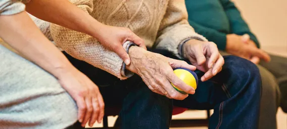 A young woman sitting next to an older man, who is holding a ball in his hand