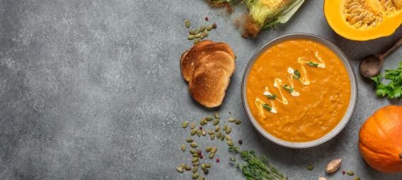 Homemade pumpkin cream soup, gray concrete background. Cozy dinner. Top view