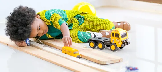 African young boy has fun with playing various type of toys.