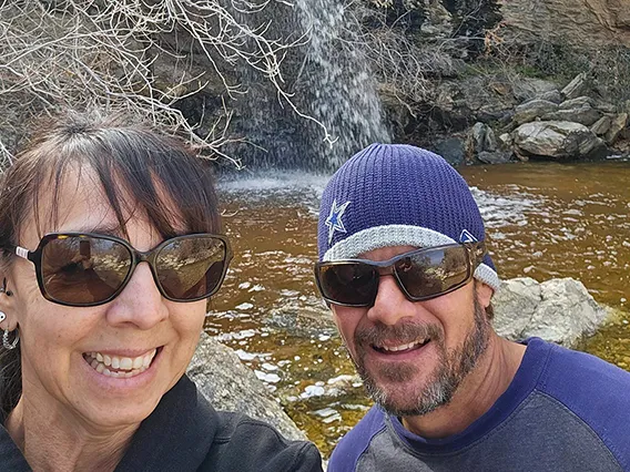 A woman and a man in front of a small waterfall