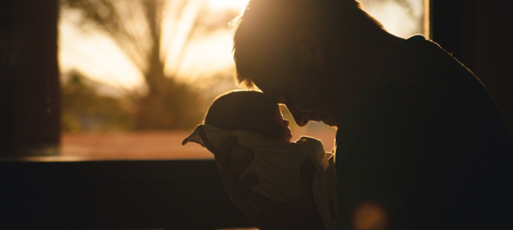 backlit photo of a dad holding a newborn baby