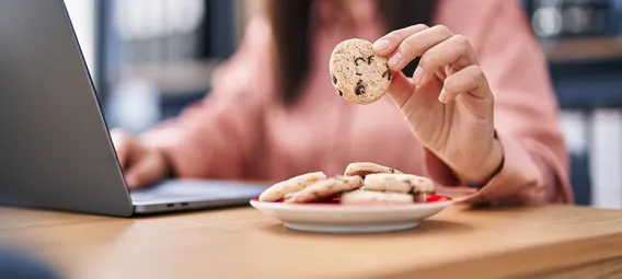 Young woman business worker using laptop eating cookies at office