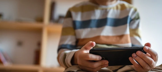 Young boy sitting on a couch with a handheld device