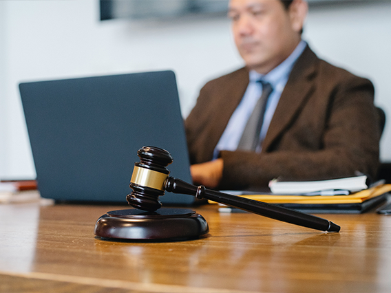 A man at a desk on his laptop with a gavel in the foreground