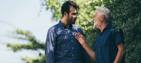 An older man talking to a young man while walking outside