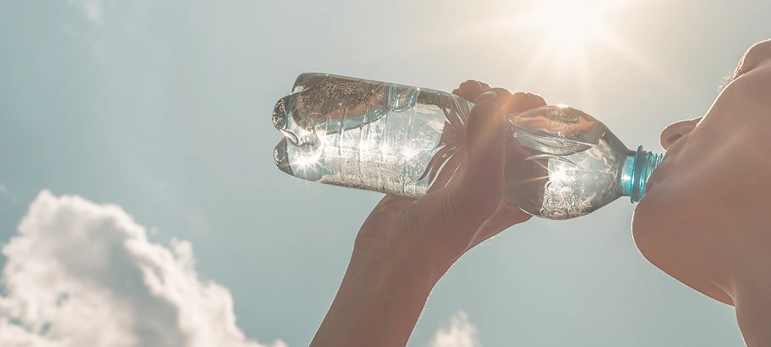 background of a blue sky and sun with a person drinking from a water bottle in front
