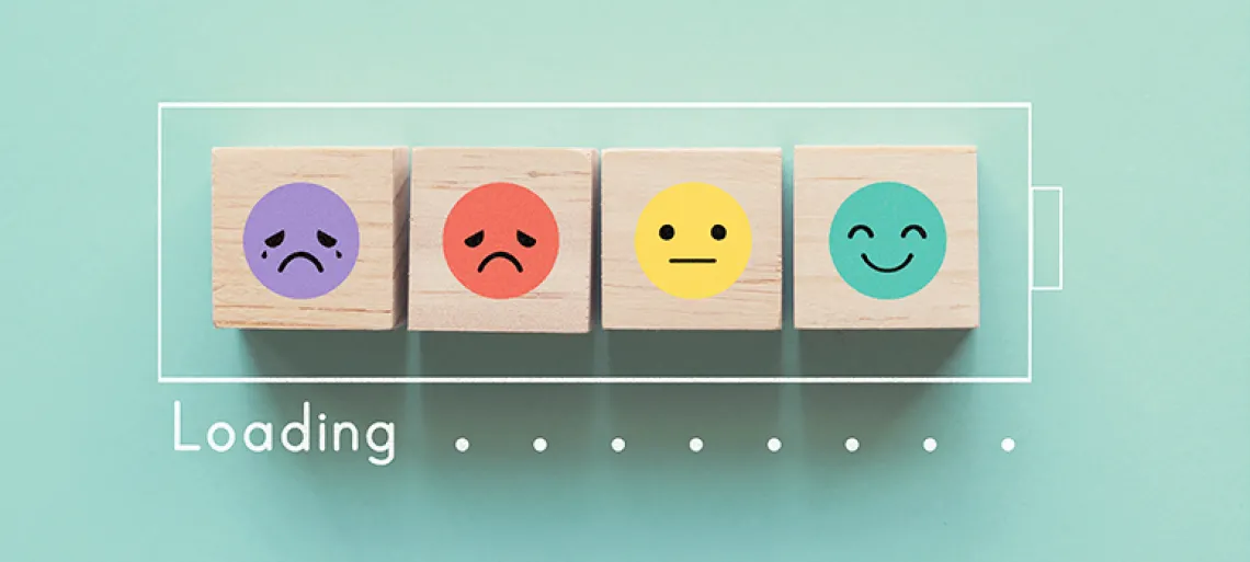 Wooden blocks with faces moving from sad to happy inside a battery outline with the word loading