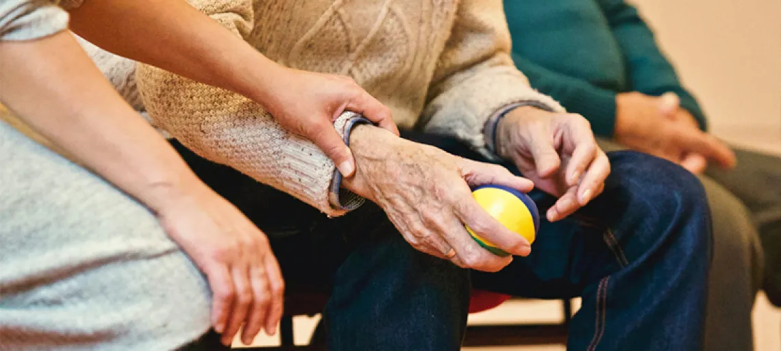 A young woman sitting next to an older man, who is holding a ball in his hand