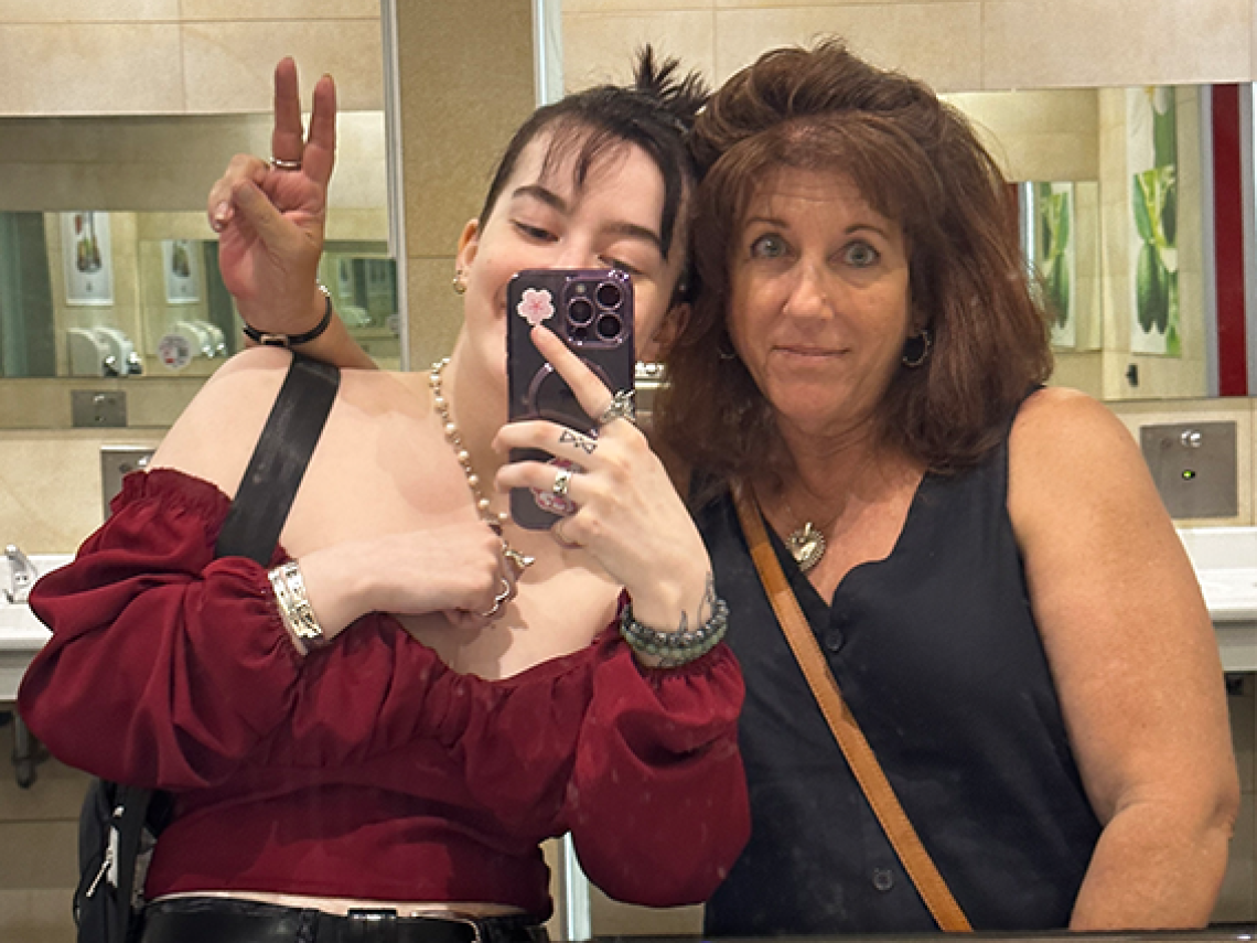 Two women taking a selfie through the bathroom mirror