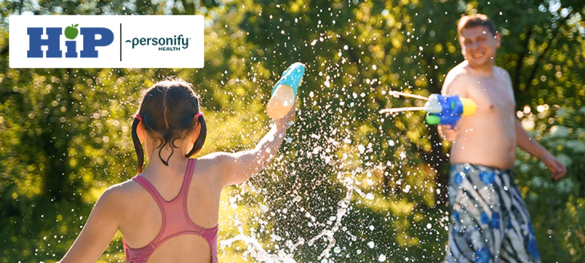 Little girl in swimwear, father play water pistols,