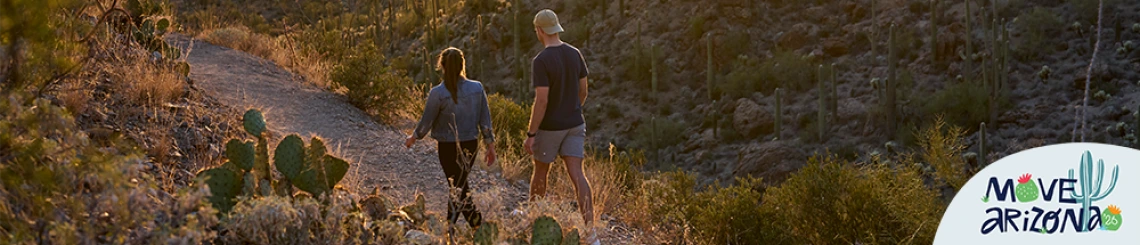 Two people walking in Gates Pass with a Move Arizona 2026 graphic in the lower right-hand corner