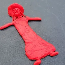 Red play doh shaped as a person wearing a hat