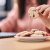 Young woman business worker using laptop eating cookies at office