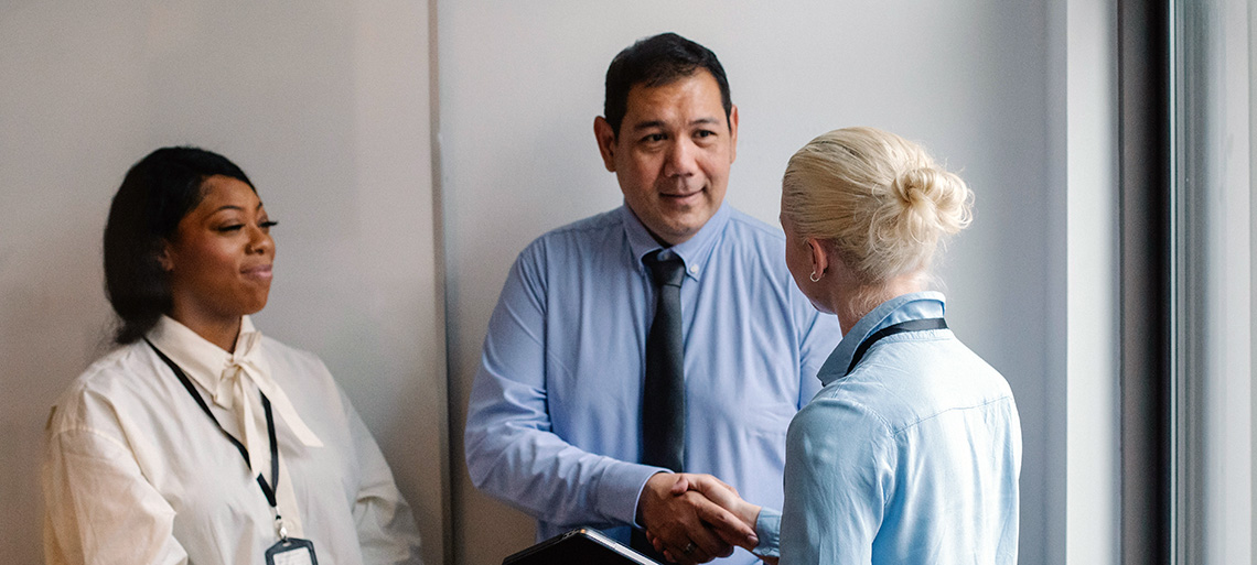 Three colleagues shaking hands in a hallway