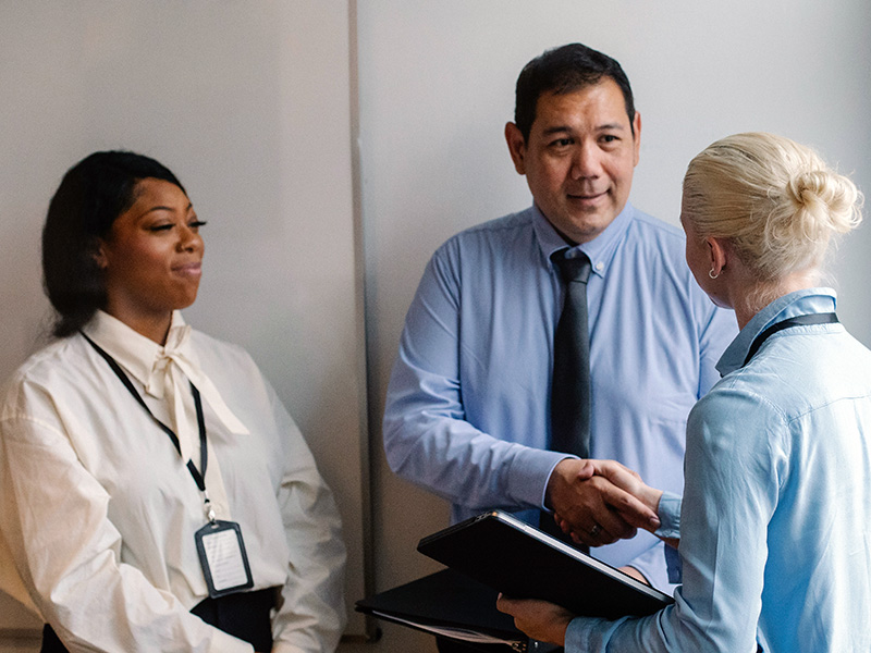 Three colleagues shaking hands in a hallway